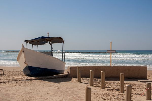 A white boat with small canopy lying on the beach